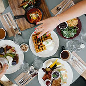 Händer tar av frukost på dukat bord