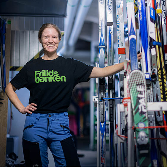 Kvinna med t-shirt med texten Fritidsbanken vid skidor för utlåning