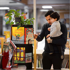 Pappa och barn vid bokhylla på bibliotek