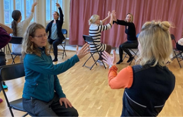 Personer sitter på stolar och dansar i par i en danssal